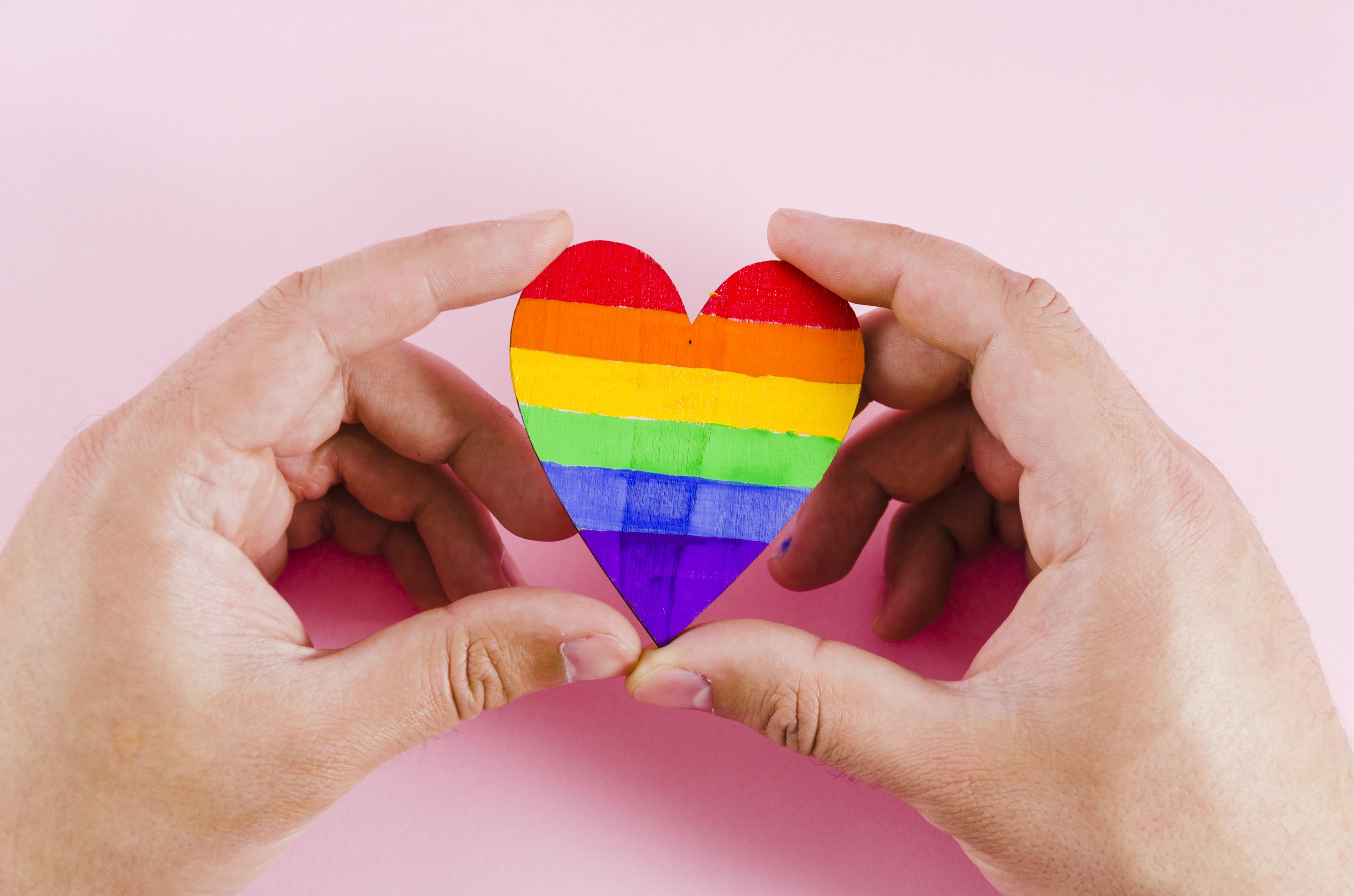 Hands cupping a rainbow heart